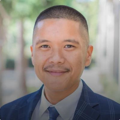 HOA attorney / HOA law A man with a buzzed head and a mustache, wearing a suit and tie, smiling at the camera