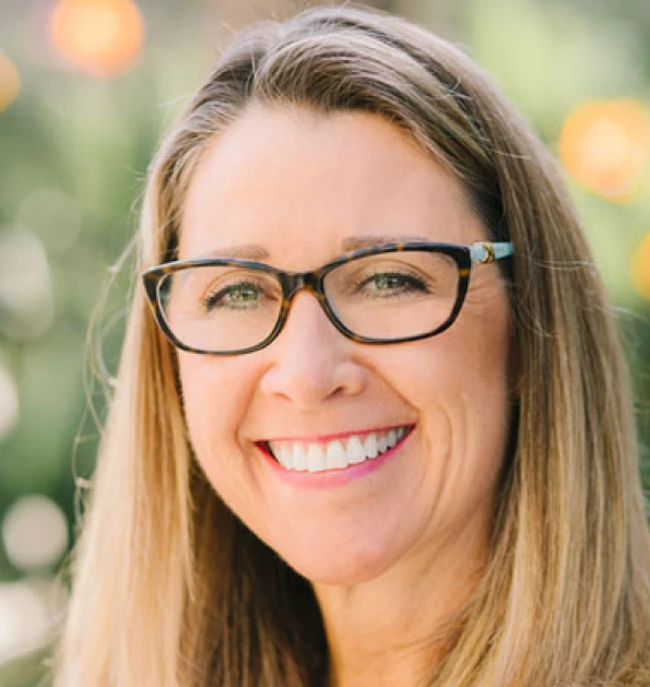 HOA attorney / HOA law A woman with long blonde hair and glasses smiling at the camera